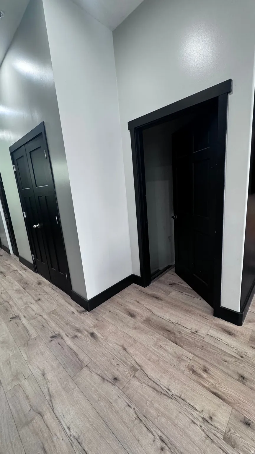 Wood-finish flooring with black trim and white walls