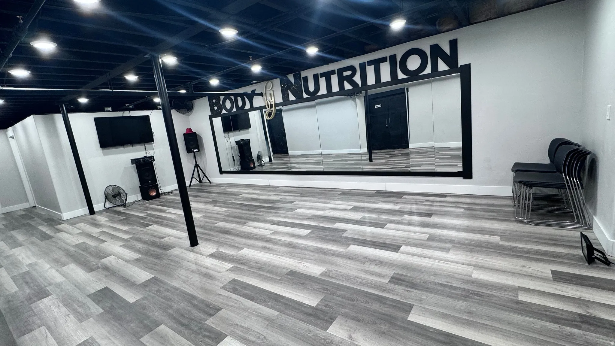 Expansive room featuring wood-finish flooring, a wall-mounted mirror, and recessed lighting