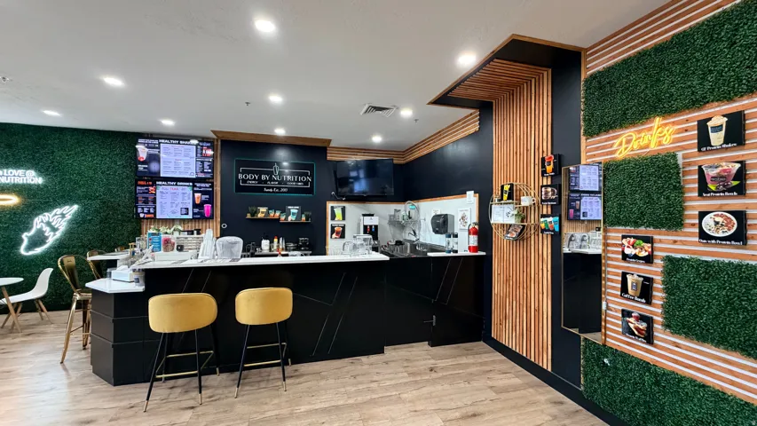 Modern service counter with a stone-finish countertop, wood-finish flooring, and accent walls featuring wood slat and faux greenery panels