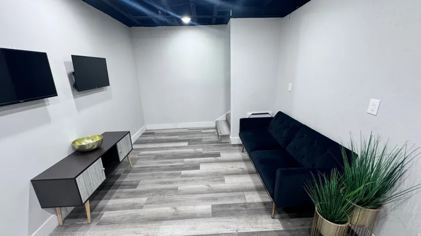 Wood-finish flooring with light gray walls, an exposed dark ceiling, and recessed lighting