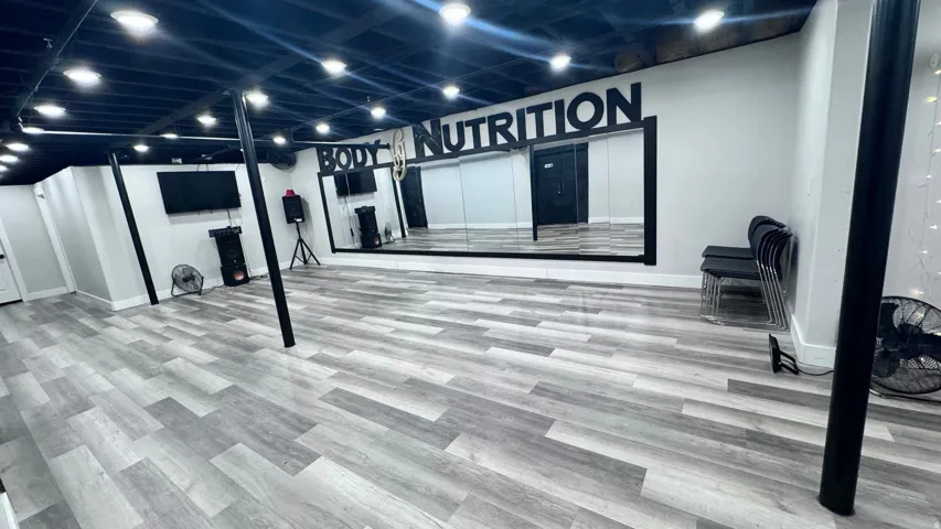 Spacious interior featuring wood-finish flooring, recessed lighting, and a full-wall mirror installation