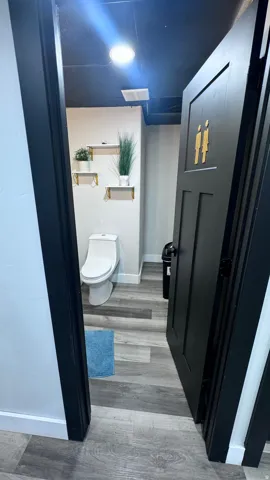 Recessed lighting illuminates the space, which features wood-finish flooring and a white toilet