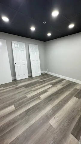 Wood-finish flooring, recessed lighting, and a dark ceiling