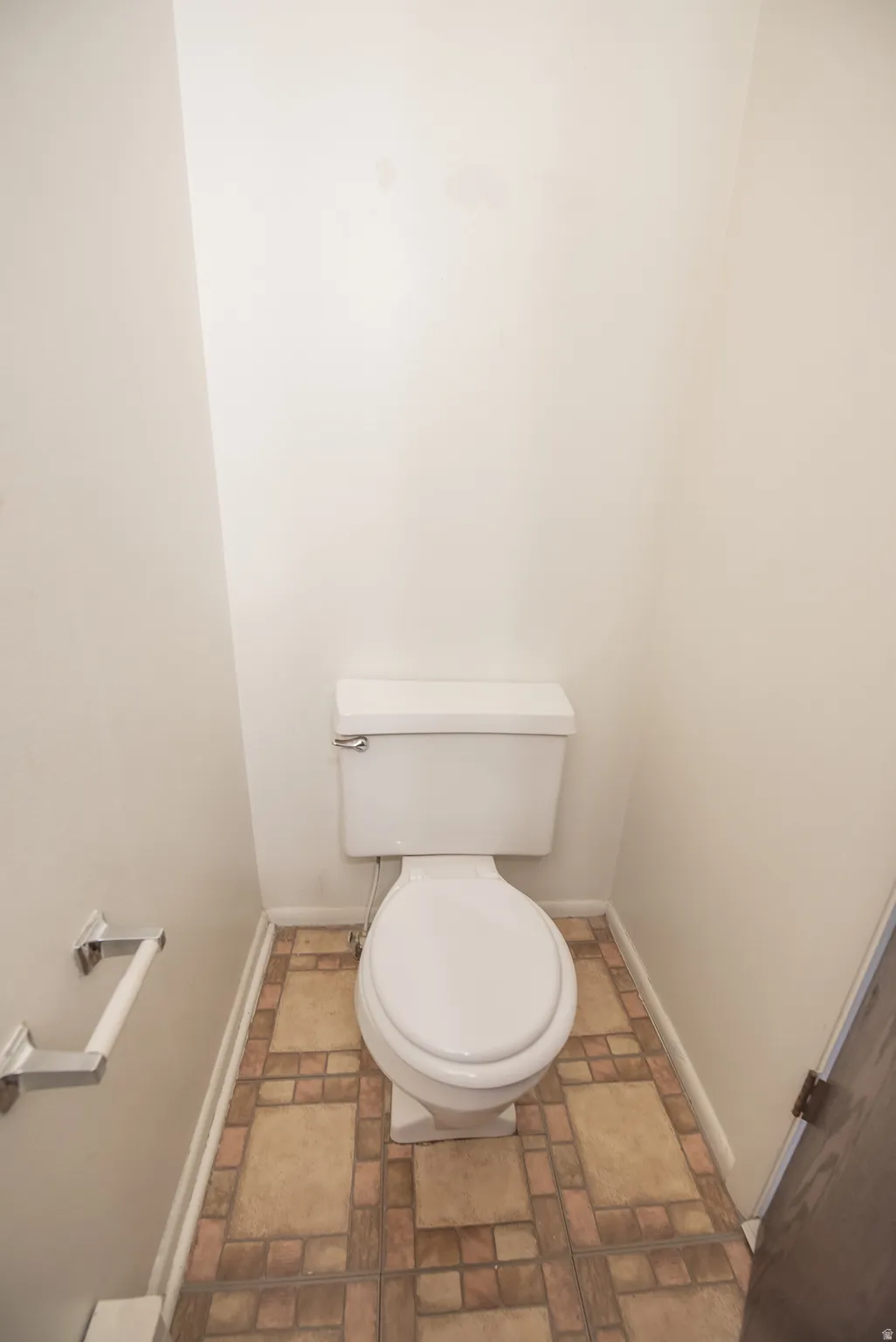White toilet with a top-mounted flush lever and a decorative tile flooring pattern