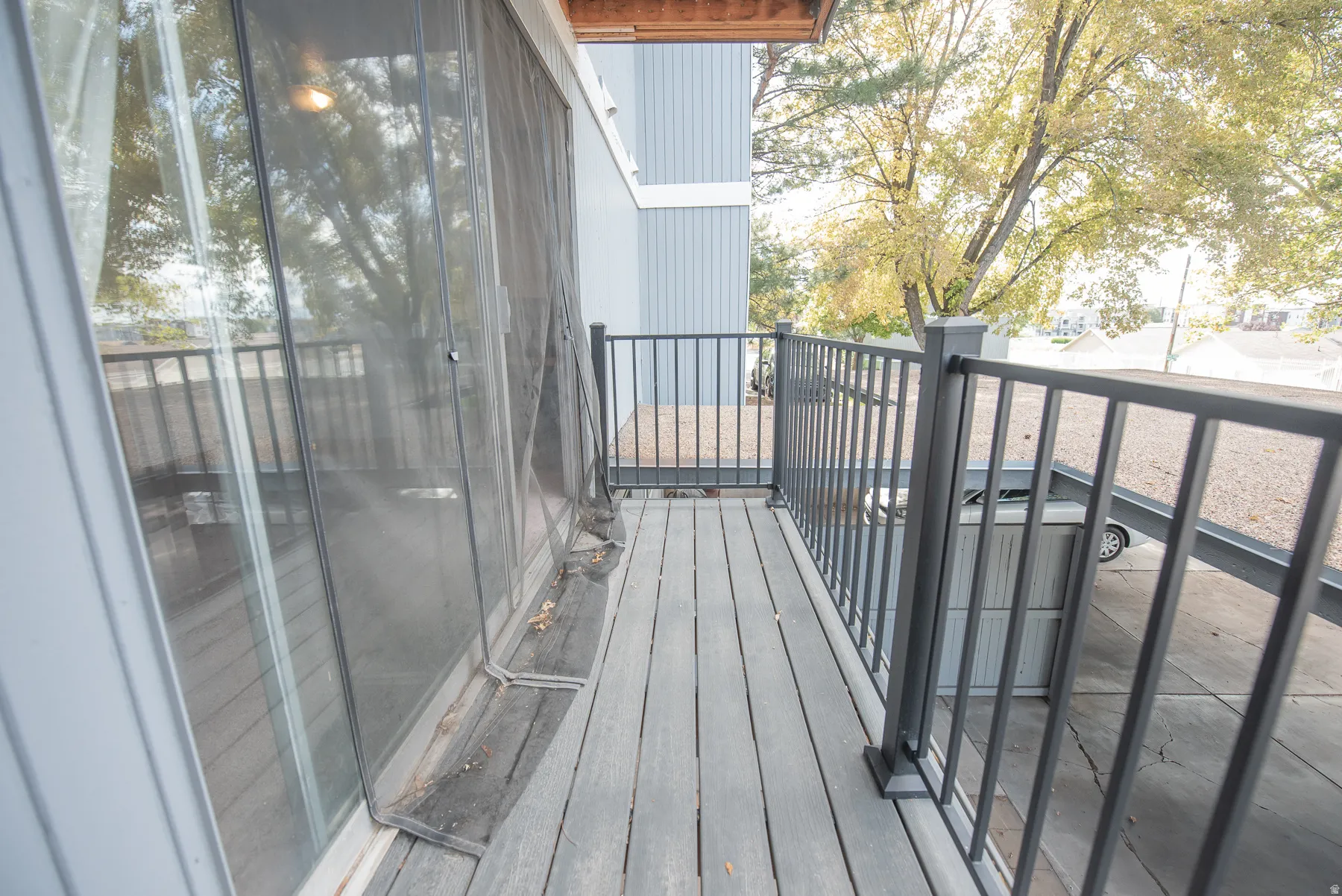 Outdoor balcony featuring composite decking, black metal railings, and sliding glass doors