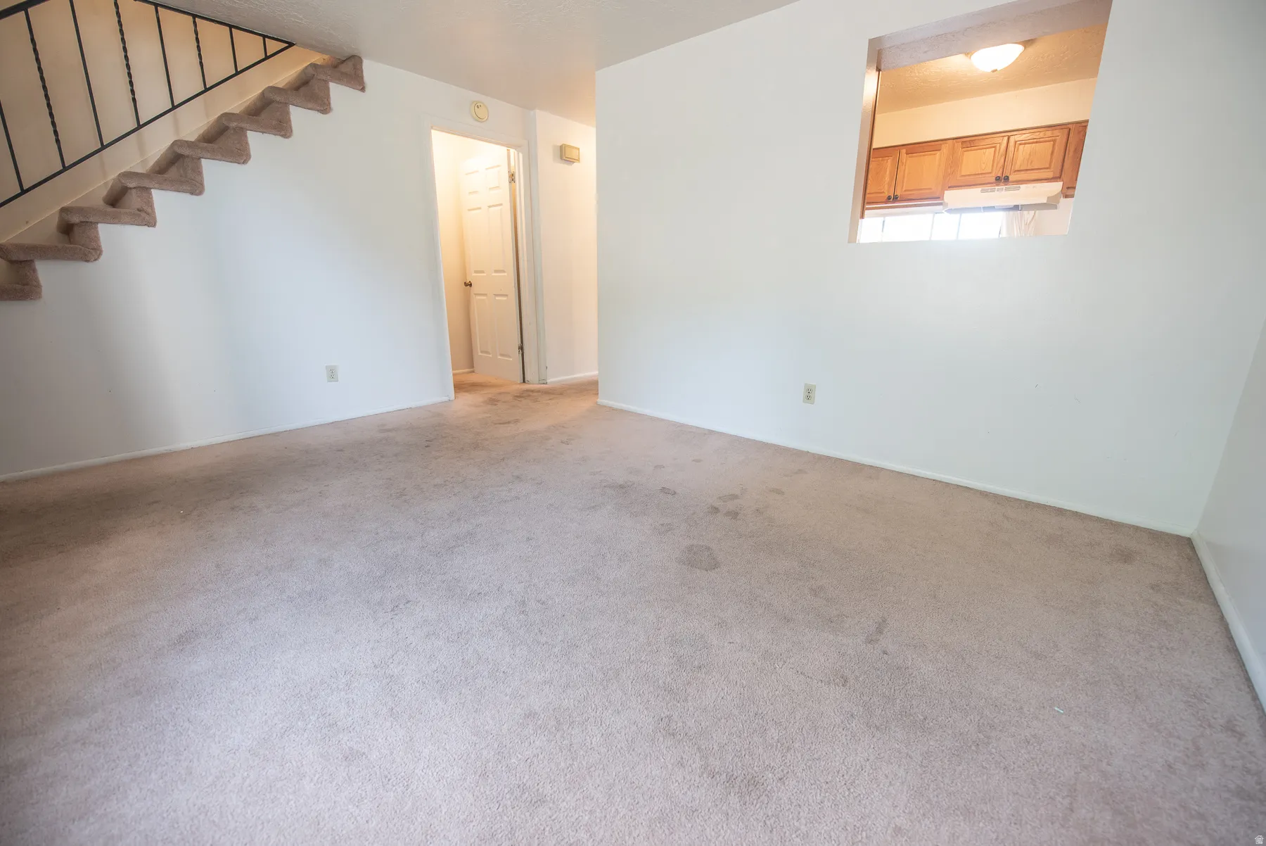 Carpeted flooring with white wall finishes, an interior window feature, and a staircase with metal railing