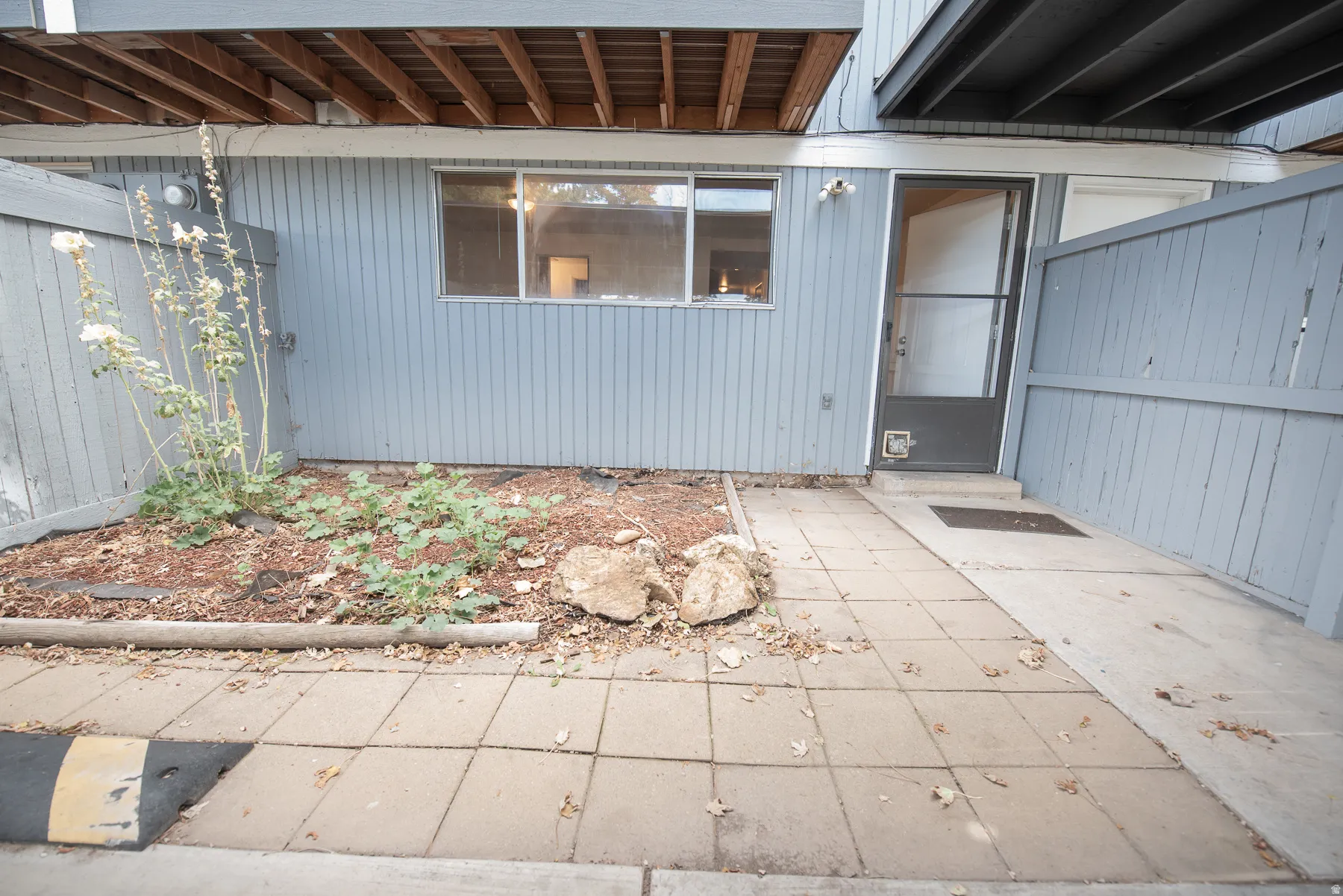 Ground-level patio area featuring concrete pavers and a wood-slat privacy fence
