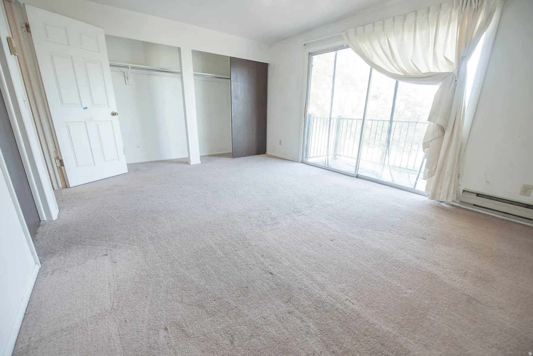 Wall-to-wall carpeting, sliding glass doors, built-in closet with hanging rods, and a white six-panel door
