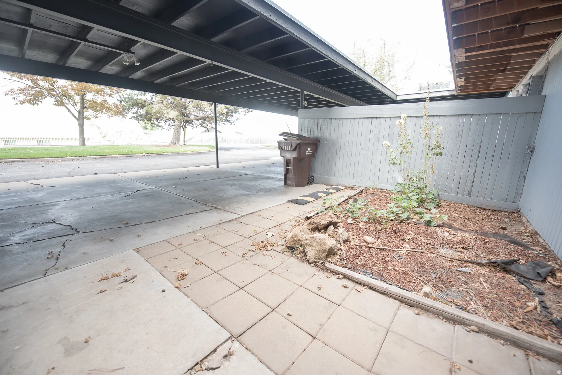 Covered parking structure with a paved driveway and an adjacent planter bed
