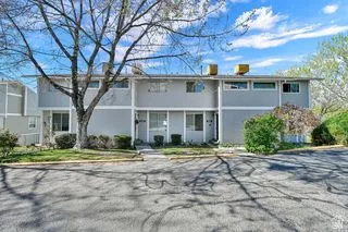 Two-story stucco exterior with multiple windows, individual entryways, and mature landscaping
