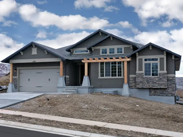 Stucco exterior with stone veneer accents, multi-pane windows, covered entry with wood pergola, and an attached garage with a concrete driveway