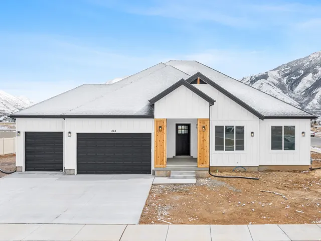 Contemporary white exterior with dark trim accents, featuring a prominent front entry with wood-clad columns, an attached two-car garage, and a concrete driveway