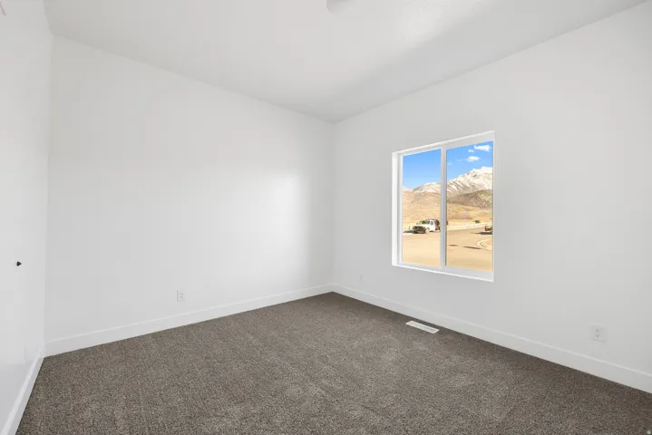 Neutral wall paint, plush carpet flooring, and a large window with mountain scenery