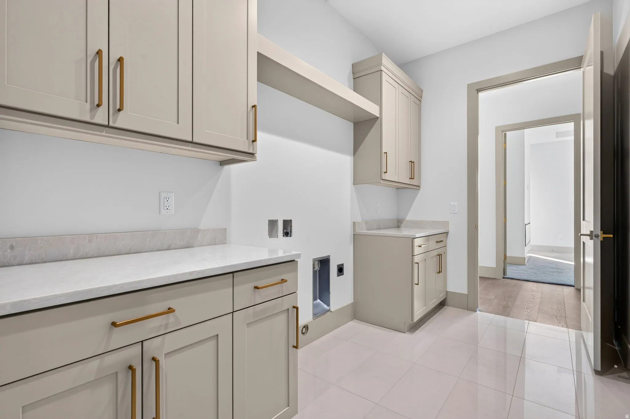 Cabinetry with gold-tone hardware, white countertops, tile flooring, and a dedicated appliance space