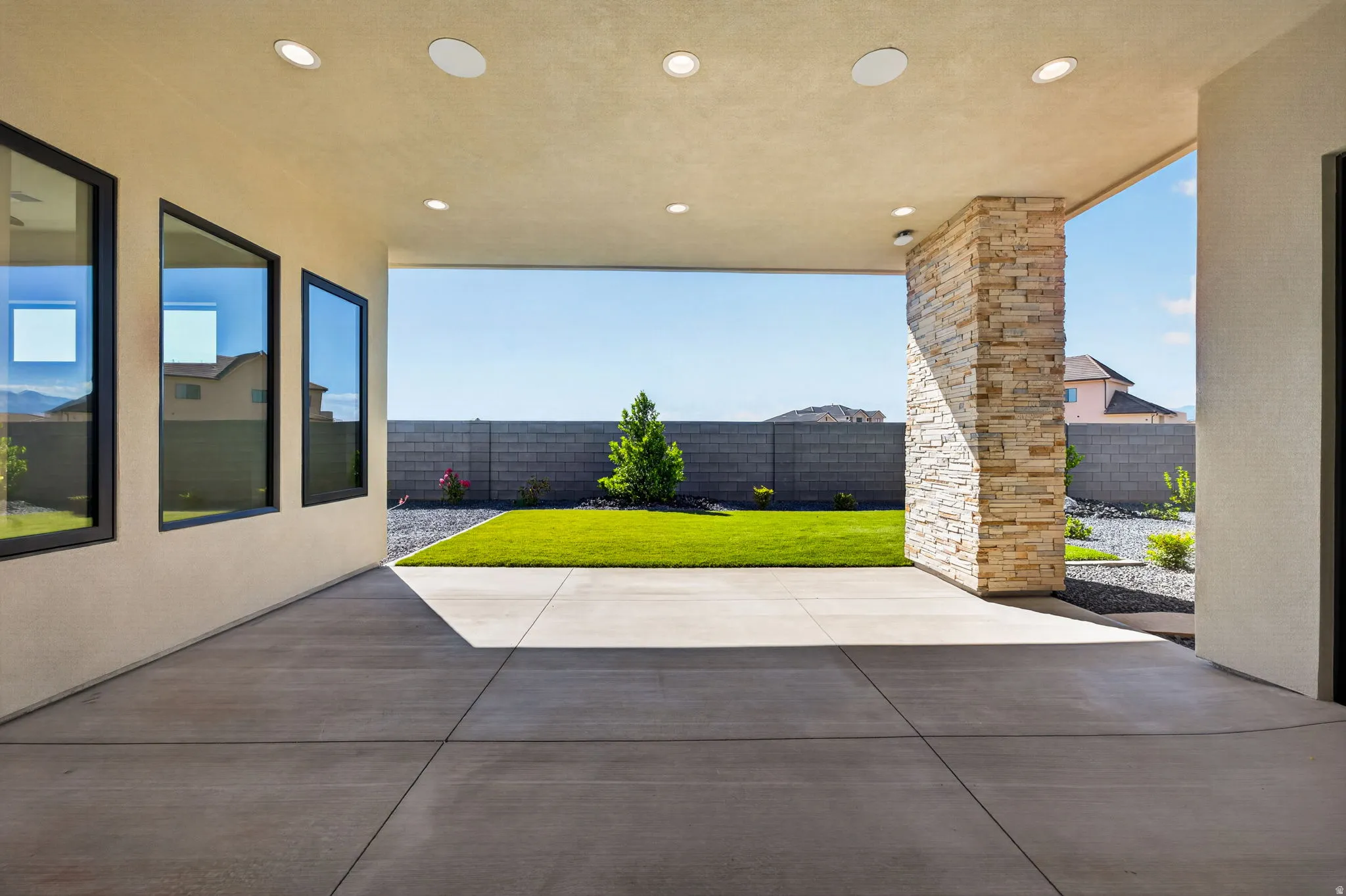 Covered patio with recessed lighting, integrated speakers, and a stacked stone accent column