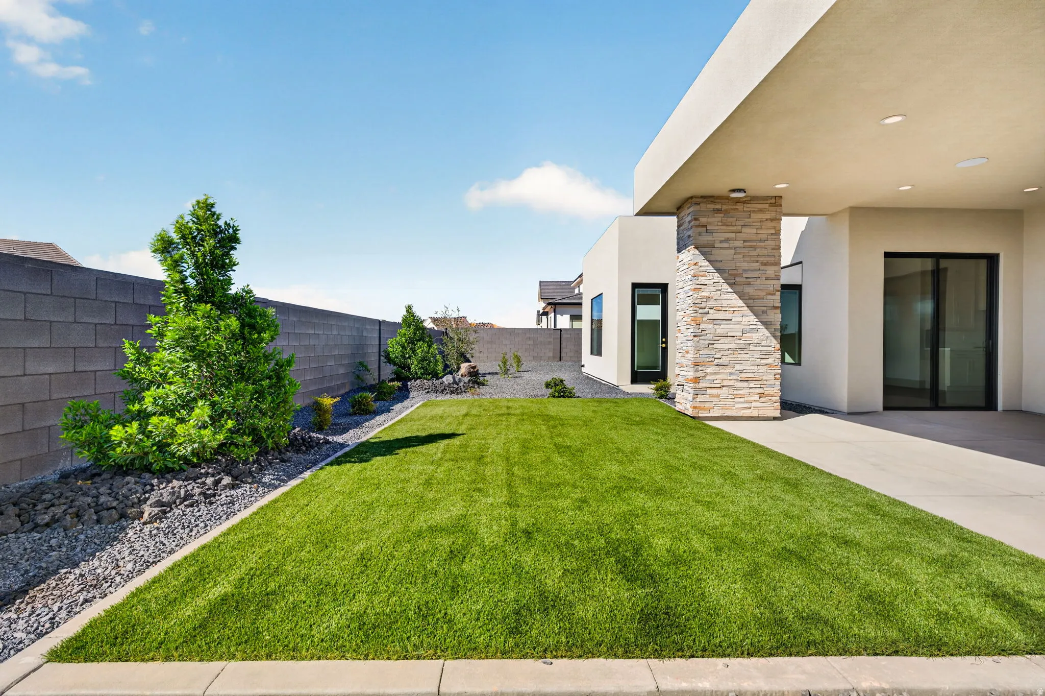 Manicured lawn with a gravel border, block wall perimeter, and established landscaping