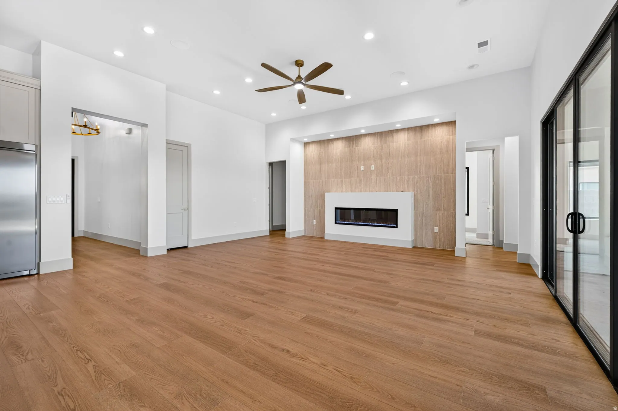Expansive living space featuring wood-finish flooring, recessed lighting, and an electric fireplace with a decorative wood-paneled accent wall