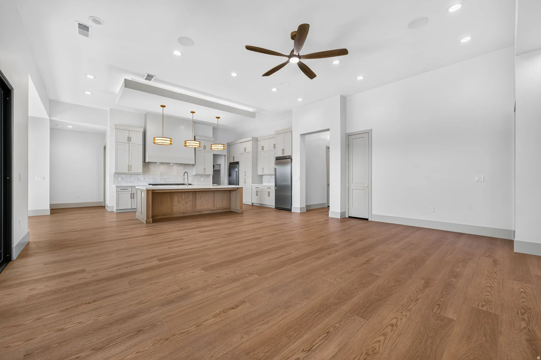 Open-concept living space with wood-finish flooring, recessed lighting, and a ceiling fan