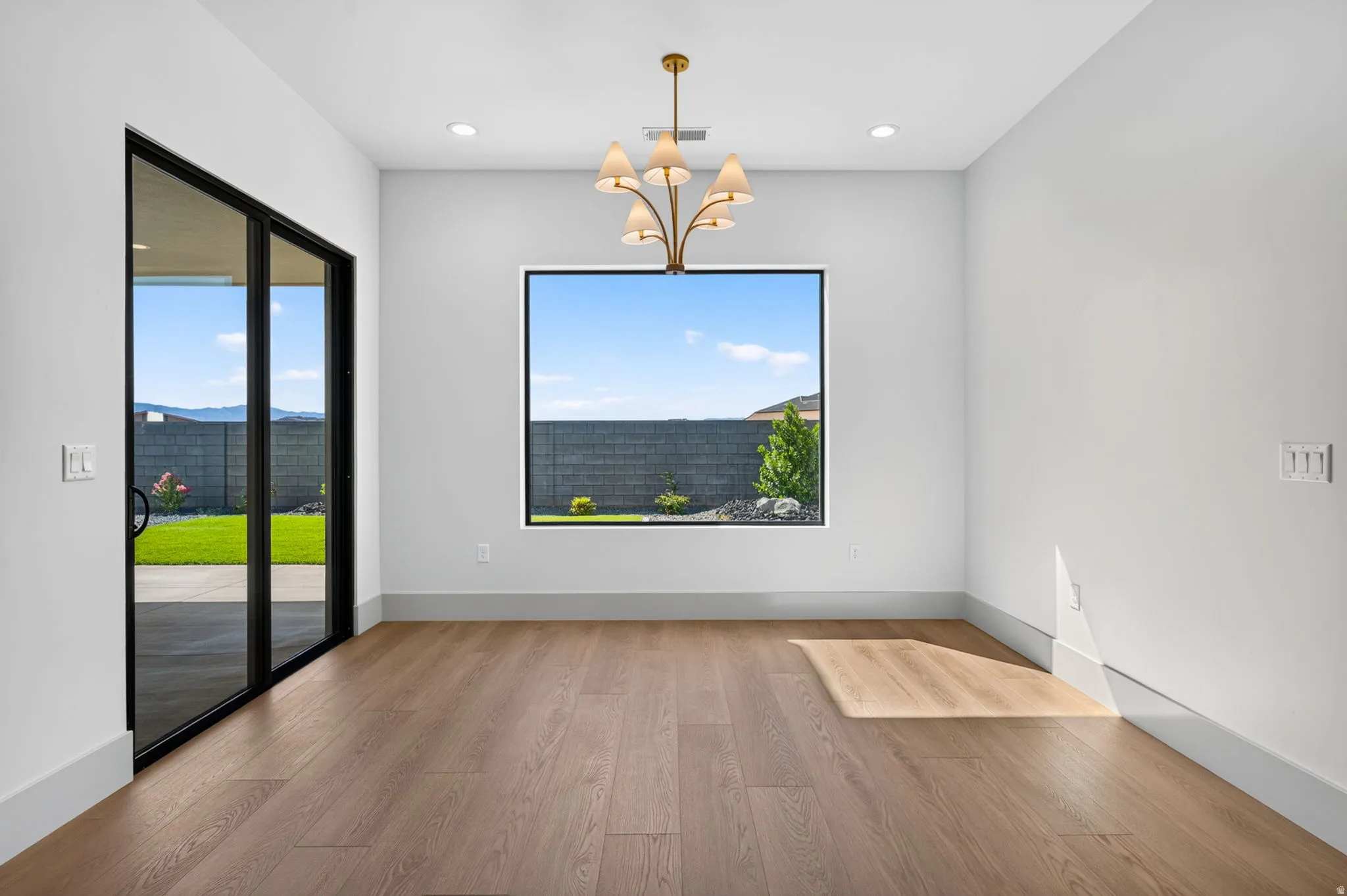 Wood-finish flooring, a contemporary chandelier, recessed lighting, and a large picture window