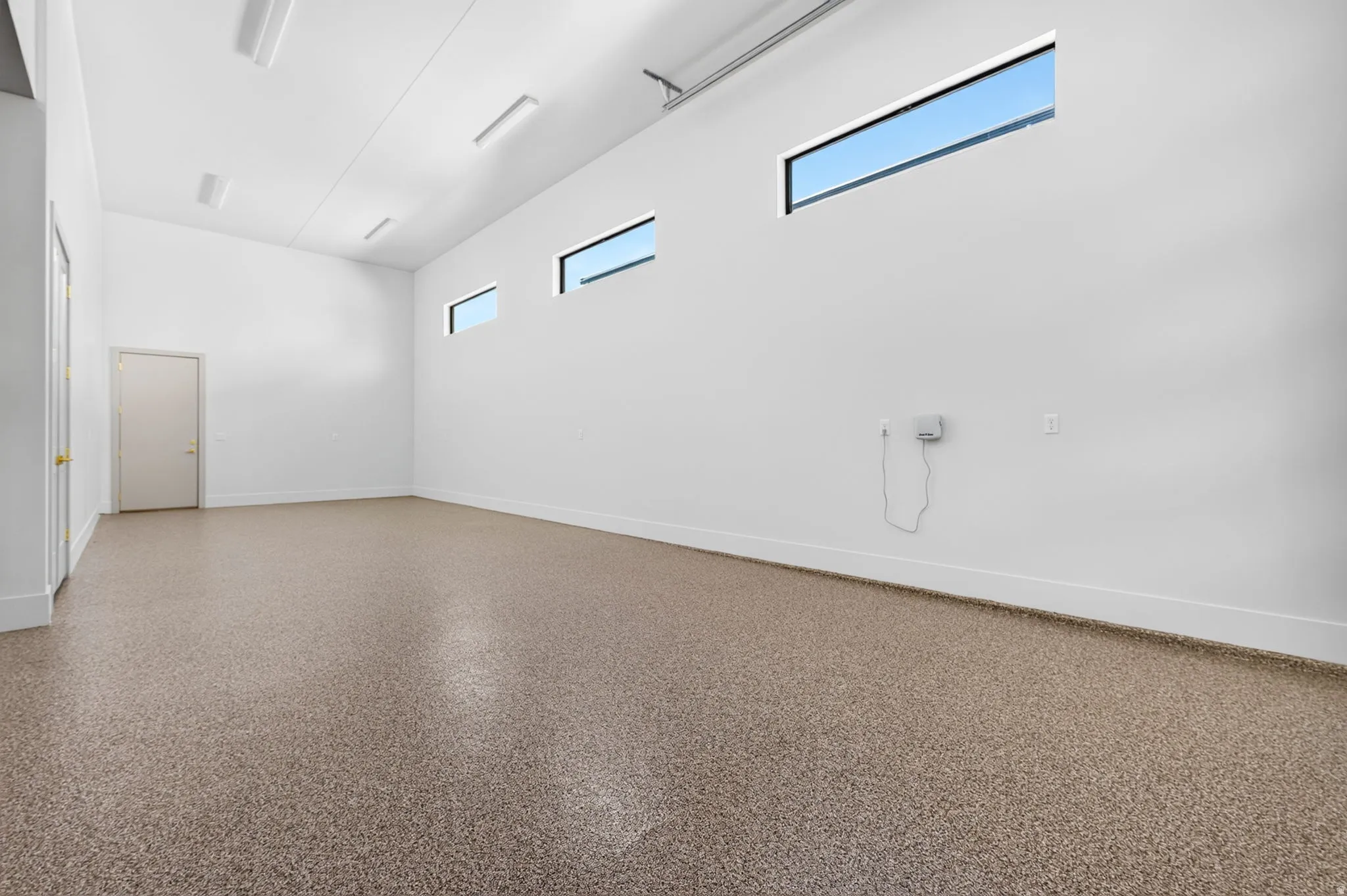 Spacious interior with an epoxy finished floor, white walls, and multiple elongated clerestory windows