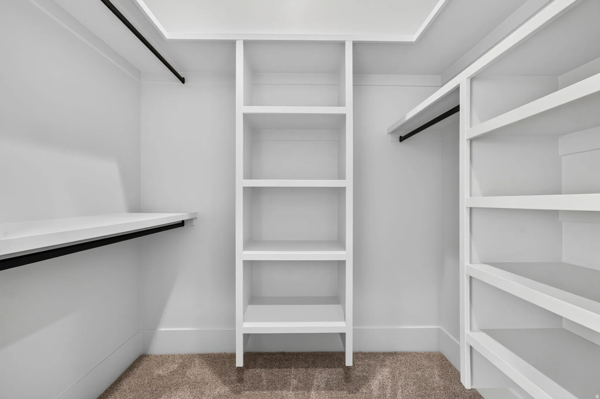 Built-in custom shelving, multiple clothing rods, clean white finish, and neutral carpet