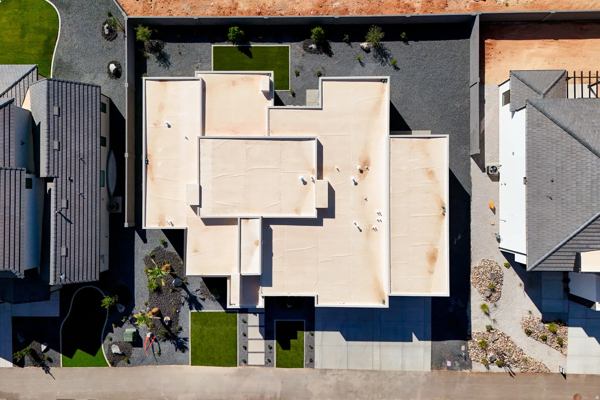 Modern flat-roof architecture with integrated landscaping, featuring concrete pathways, artificial turf accents, and gravel beds