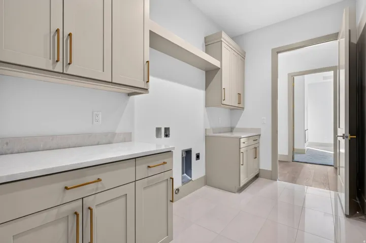 Cabinetry with gold-tone hardware, white countertops, tile flooring, and a dedicated appliance space