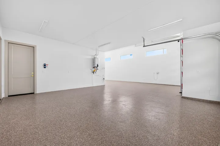 Spacious garage featuring a durable epoxy flooring, horizontal wall windows, and a tankless water heater