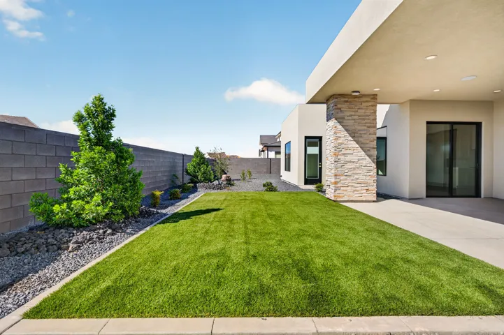 Manicured lawn with a gravel border, block wall perimeter, and established landscaping