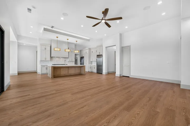 Open-concept living space with wood-finish flooring, recessed lighting, and a ceiling fan