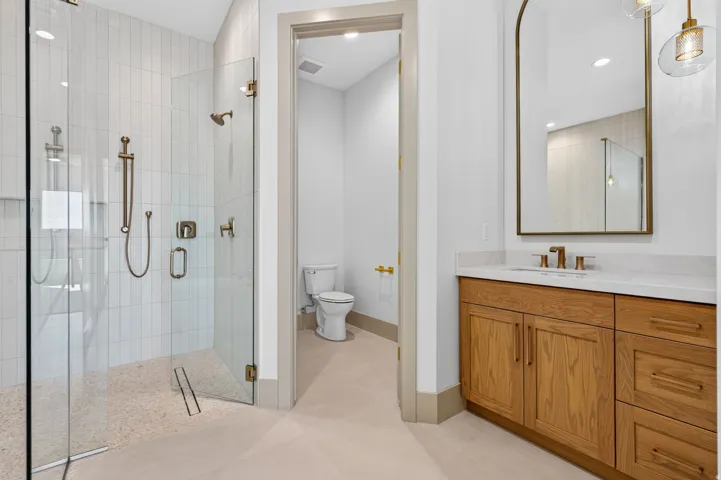 Glass-enclosed shower with vertical tile surround and integrated shower system