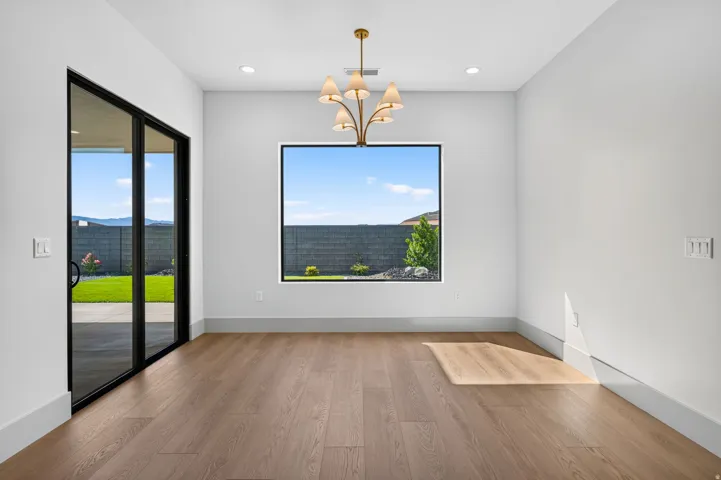 Wood-finish flooring, a contemporary chandelier, recessed lighting, and a large picture window