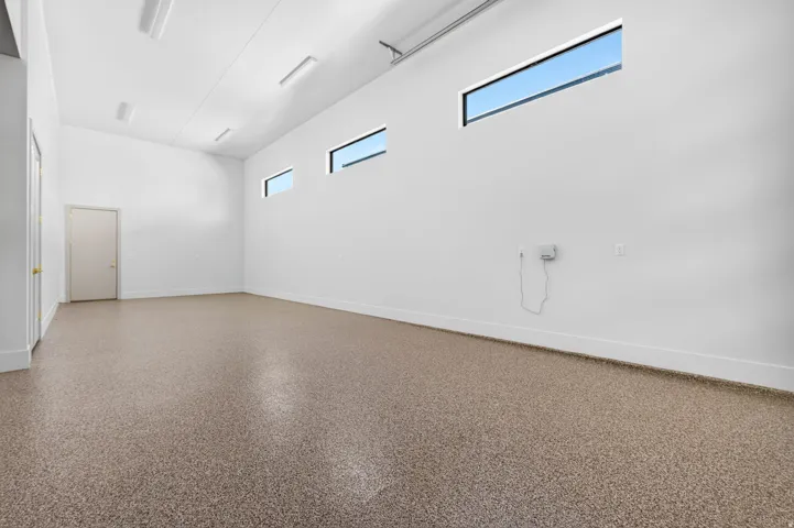 Spacious interior with an epoxy finished floor, white walls, and multiple elongated clerestory windows