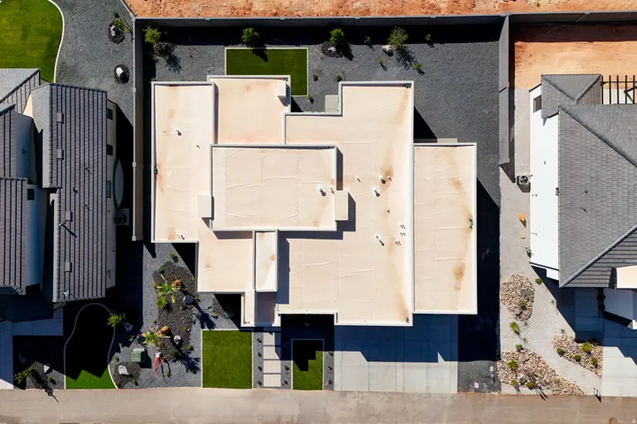 Modern flat-roof architecture with integrated landscaping, featuring concrete pathways, artificial turf accents, and gravel beds