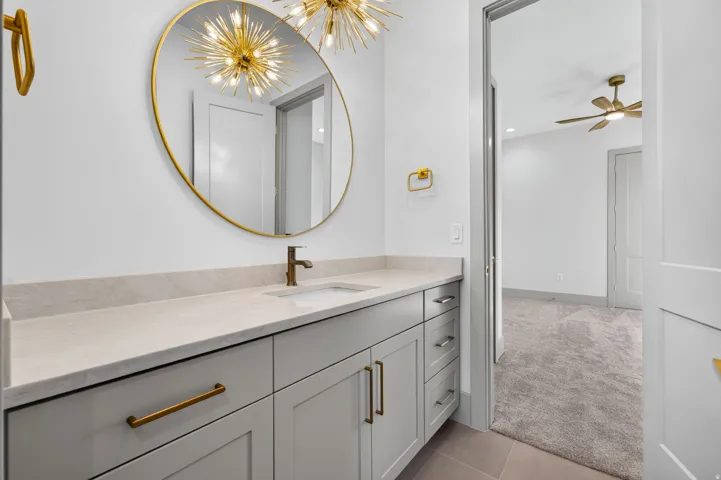 Vanity with a light-toned countertop, under-mount sink, and bronze-finish faucet