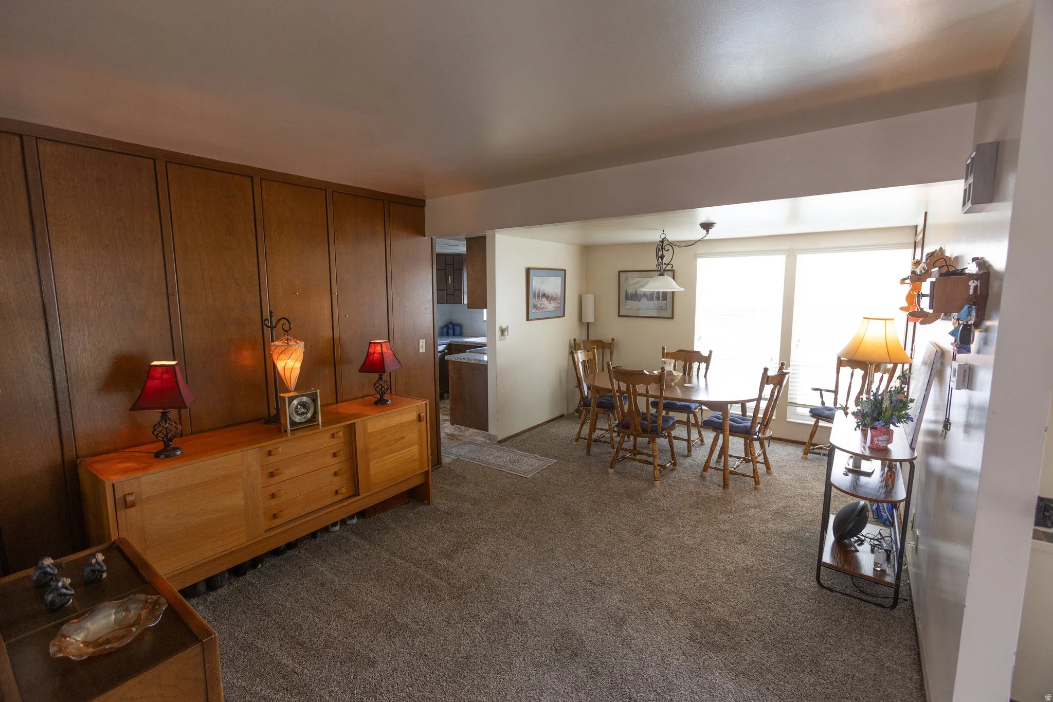 Wall-to-wall carpeting, wood-paneled wall, overhead lighting, and large windows