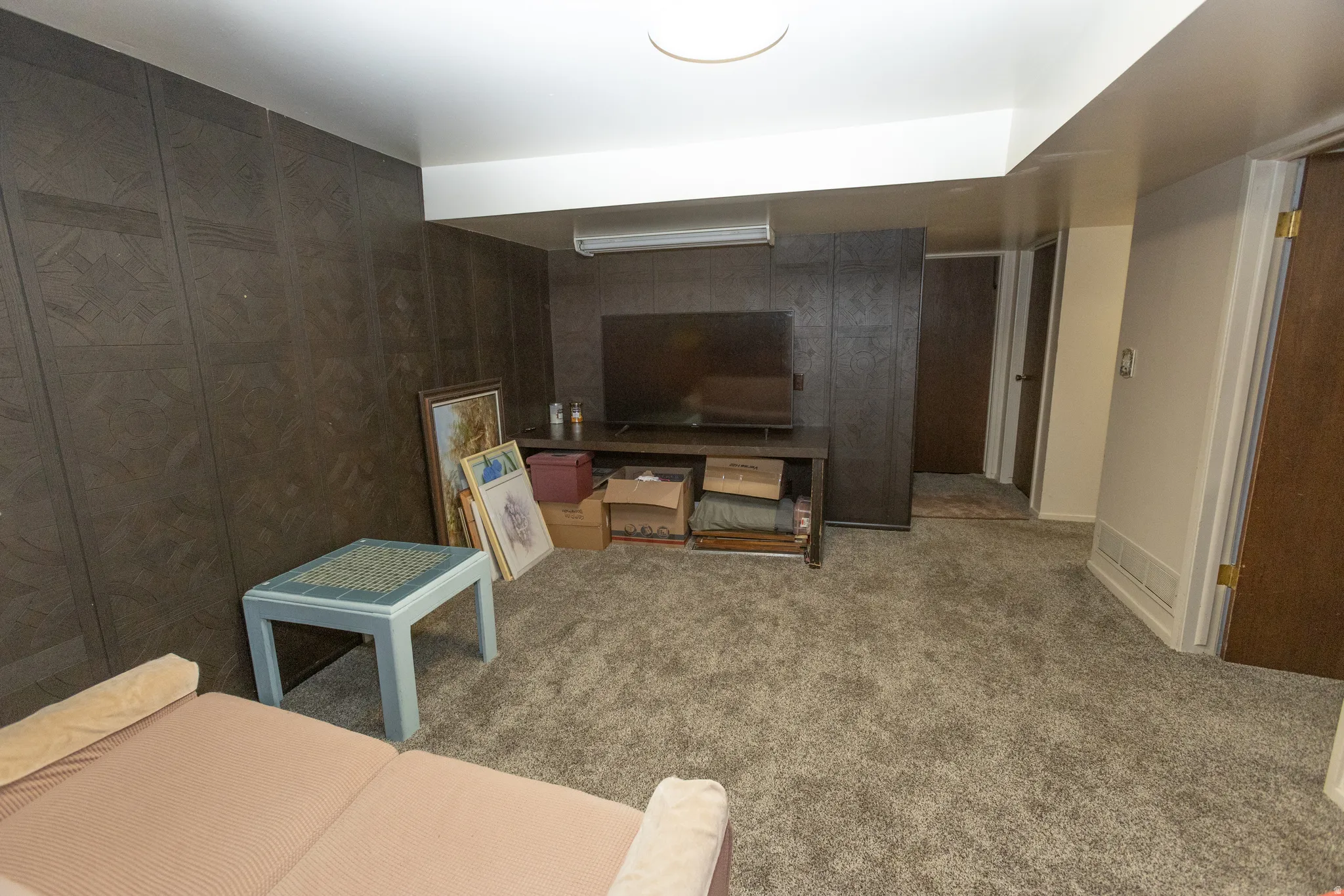 Carpeted flooring, recessed ceiling lighting, textured wall paneling, and a built-in storage cabinet