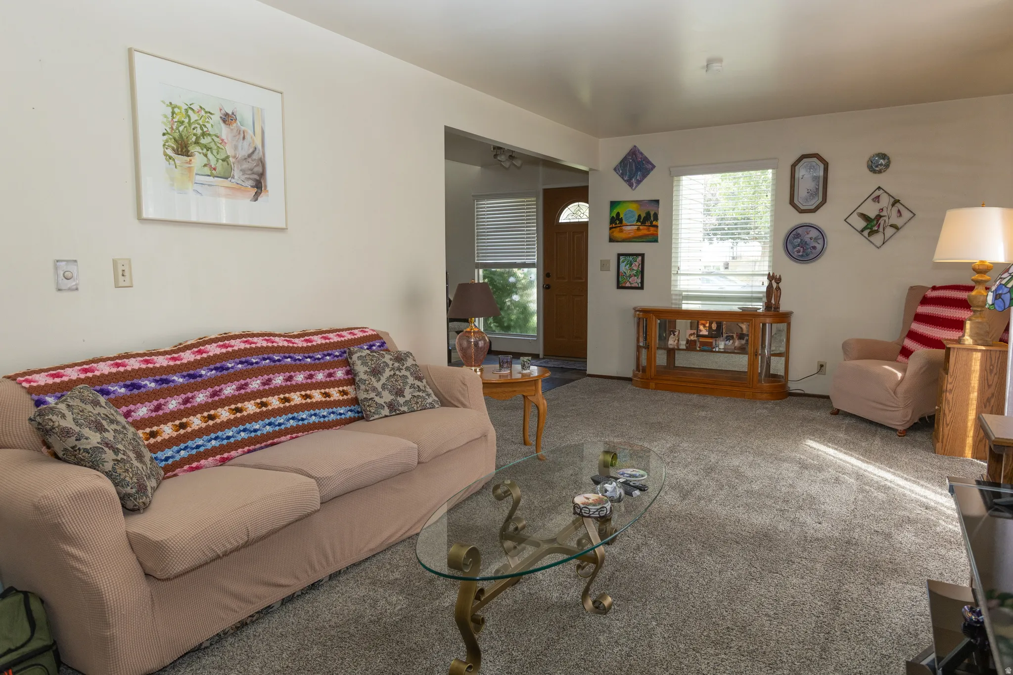 Carpeted living area featuring a front entry door with a window, a window with blinds, and white walls