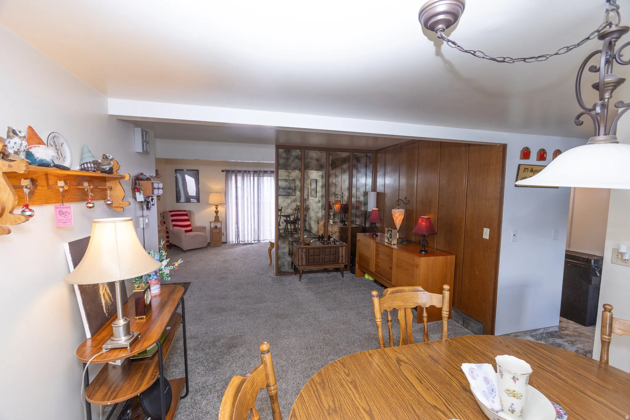 Carpeted living area with sliding glass door, wood paneling, and a decorative mirror wall