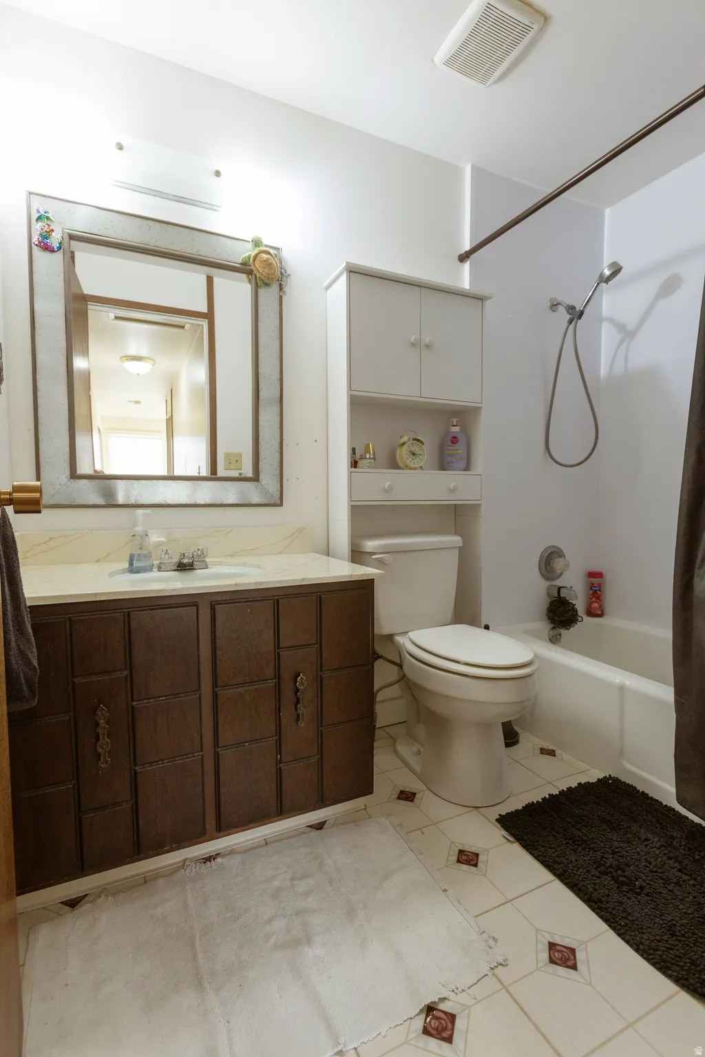 Bathroom featuring a vanity with dark wood-finish cabinetry, a framed mirror, and a built-in storage unit