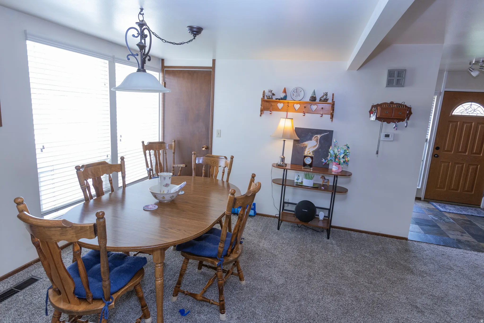 Carpet flooring, multiple windows with blinds, wood-finish interior doors, and a decorative ceiling light fixture