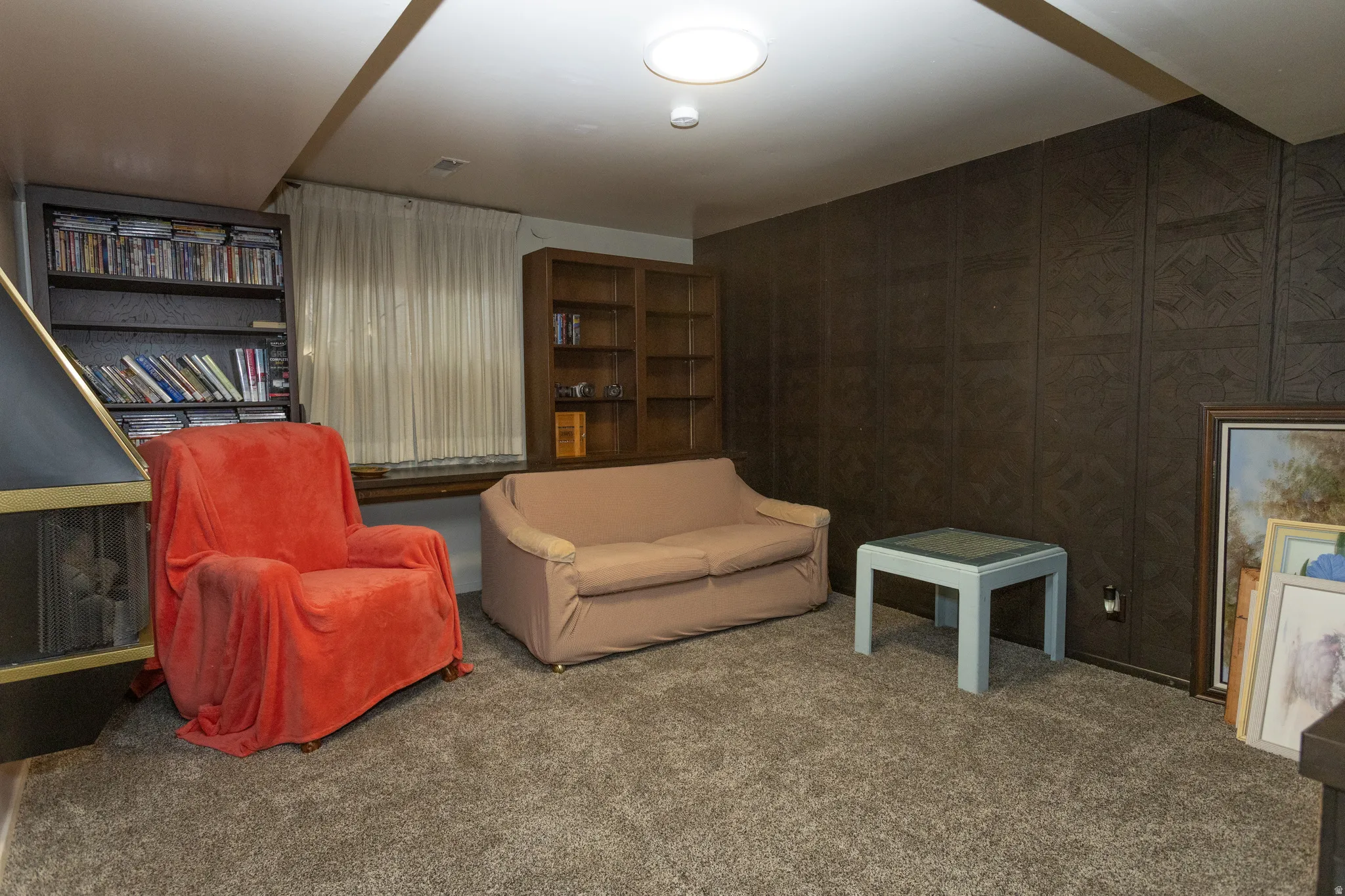 Carpeted room with a built-in fireplace, two built-in shelving units, and paneled walls