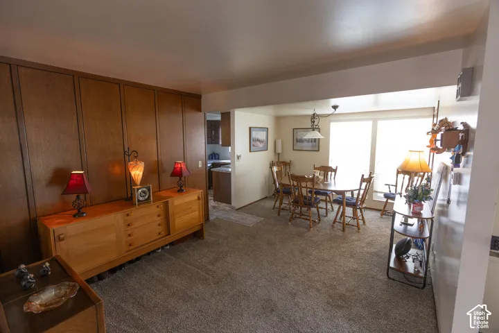 Wall-to-wall carpeting, wood-paneled wall, overhead lighting, and large windows