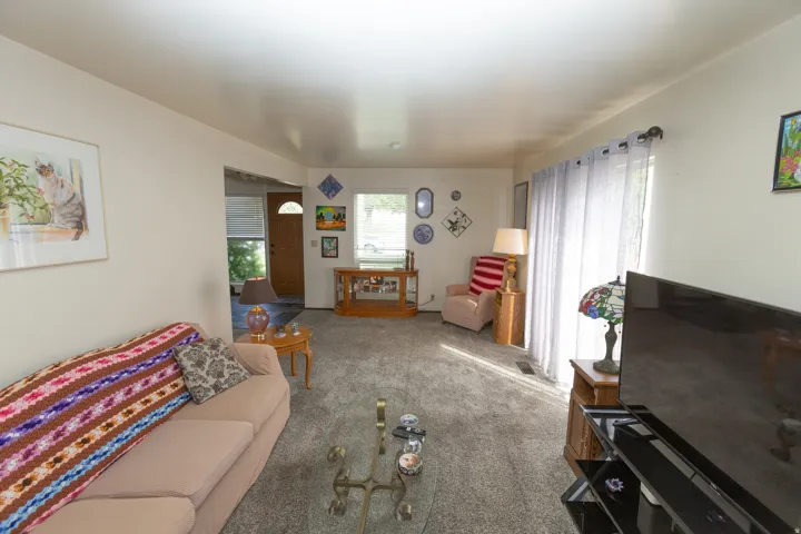 Spacious living area featuring neutral carpeting, light-toned walls, and a sliding glass door
