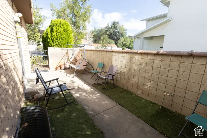 Paved patio area with faux grass accents and a concrete block privacy wall