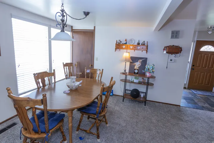 Carpet flooring, multiple windows with blinds, wood-finish interior doors, and a decorative ceiling light fixture