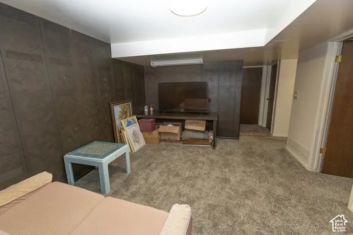 Carpeted flooring, recessed ceiling lighting, textured wall paneling, and a built-in storage cabinet