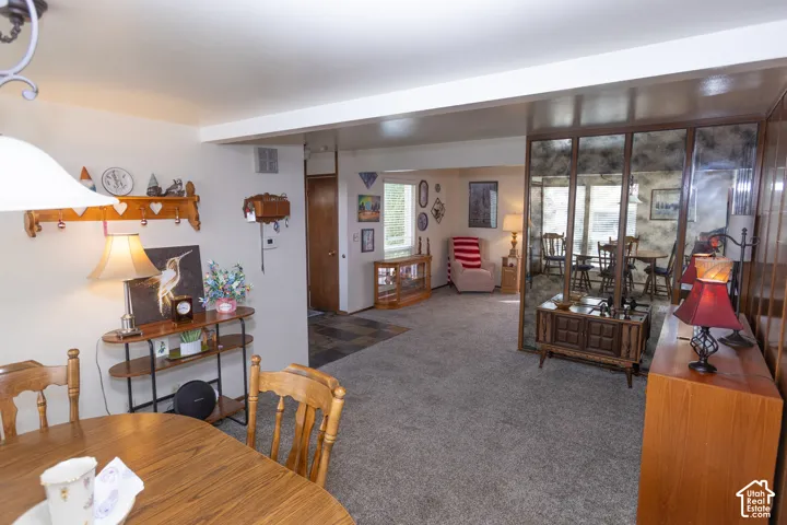 Open-concept living space with carpeted flooring and an expansive mirrored wall