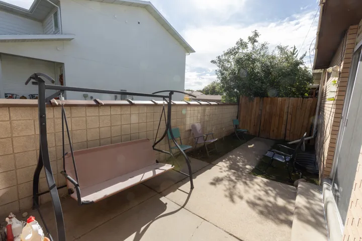 Paved patio area featuring a concrete block privacy wall and a wood-paneled fence