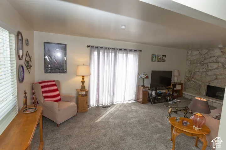 Living area with carpet flooring, sliding glass door, and a stone-clad fireplace